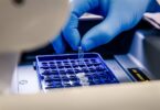 Laboratory technician loading a sample tube into a sequencing instrument for molecular analysis.
