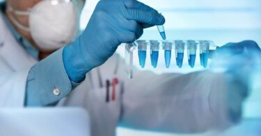 Scientist in laboratory handling blue liquid samples with pipette, representing mRNA and biotechnology research