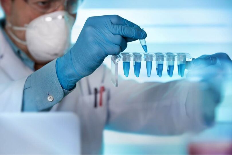 Scientist in laboratory handling blue liquid samples with pipette, representing mRNA and biotechnology research