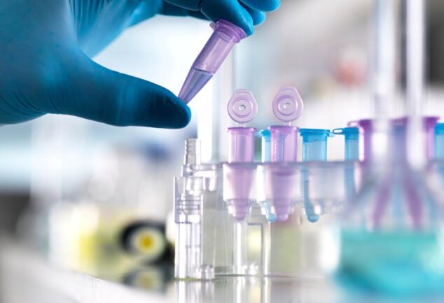 Gloved hand placing a microtube into a rack in a clinical research lab.