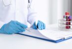 Doctor in medical gloves reviewing clinical trial documents with blood samples nearby.