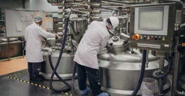 Scientists working with industrial fermentation tanks in a biotechnology facility.