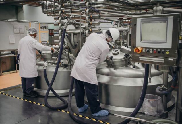 Scientists working with industrial fermentation tanks in a biotechnology facility.