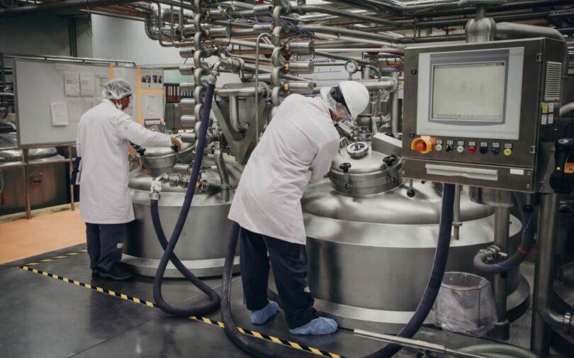 Scientists working with industrial fermentation tanks in a biotechnology facility.