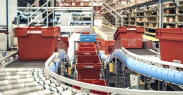 Automated conveyor system transporting crates inside PostNord TPL’s pharmaceutical distribution centre.