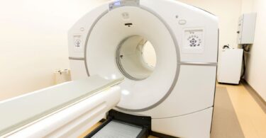 modern MRI machine in a hospital suite, with patient bed and scanner bore visible