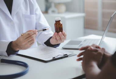 Stock photo of a doctor and a pharmacist discussing medicines, illustrating prescribing and dispensing of treatment.