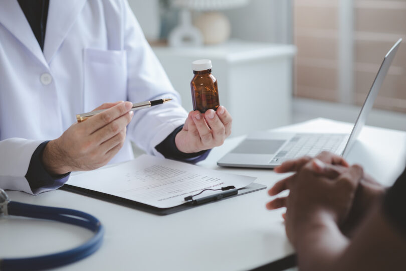 Stock photo of a doctor and a pharmacist discussing medicines, illustrating prescribing and dispensing of treatment.