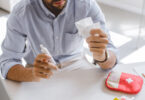 Cropped view of a person in an office holding a nasal spray and a tissue.
