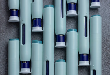 Close-up of several syringe-style self-injection pens arranged on a rustic gray kitchen counter.